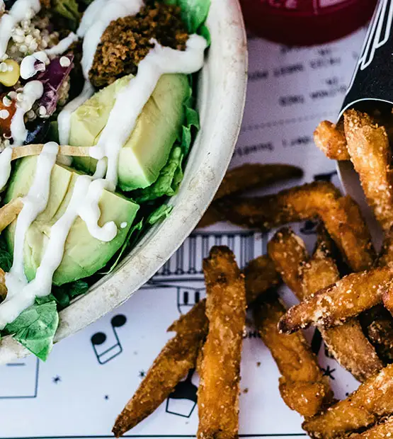 A salad and crispy french fries- drizzled with sauzzy sauces low calorie, healthy sauces